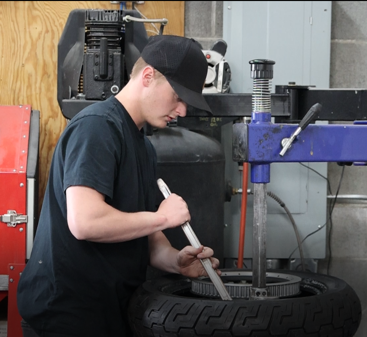 A Fastback Moto technician mounting a tire in the shop